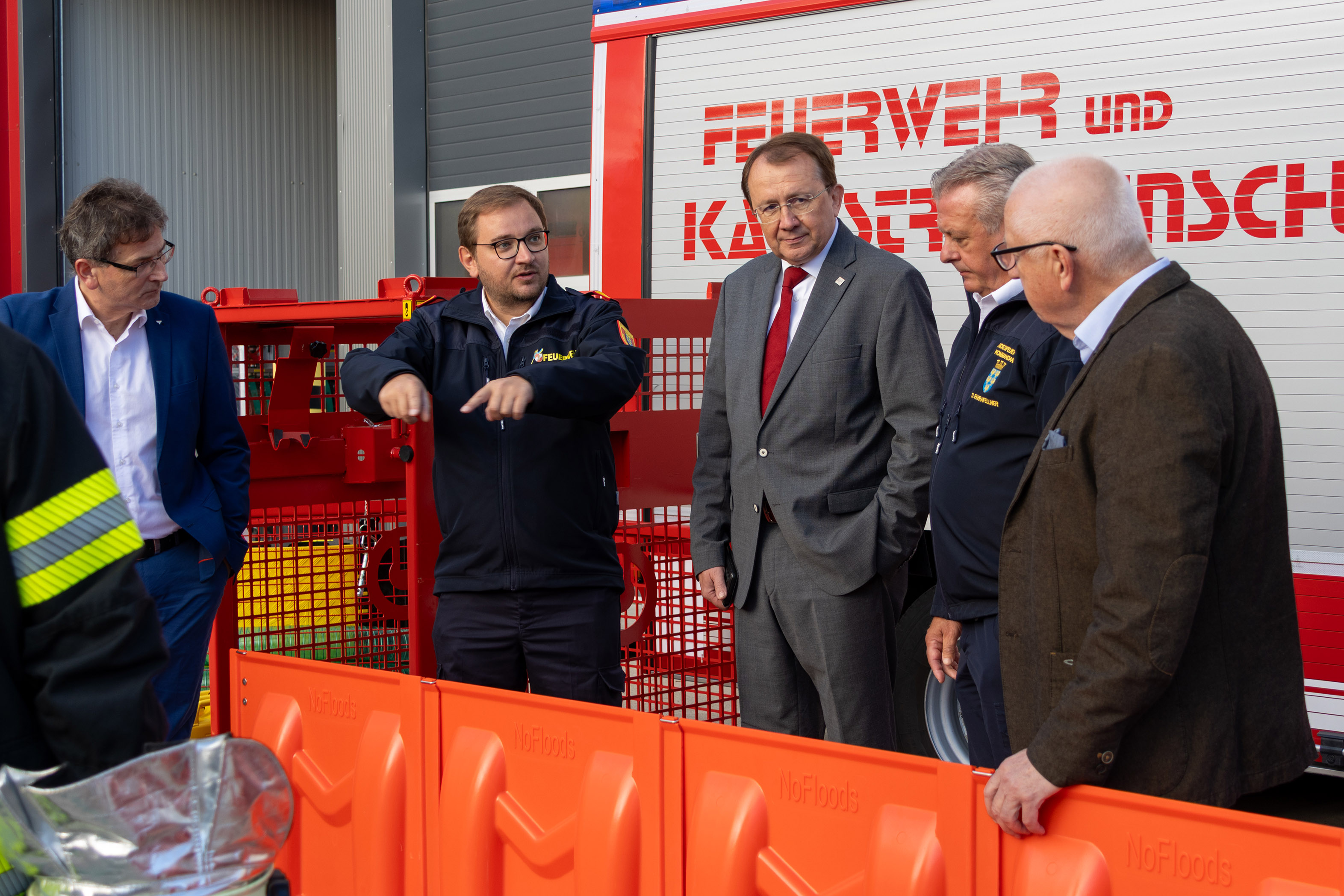 Feuerwehr Kaernten: Landesrat Daniel Fellner mit Feuerwehrleuten vor einem roten Feuerwehrfahrzeug.